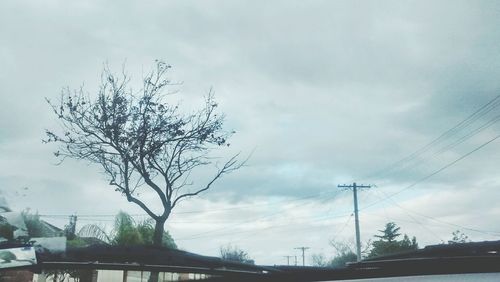 Low angle view of power lines against cloudy sky