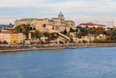 Buildings by river against sky