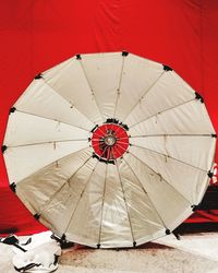 Close-up of umbrella on floor against red wall