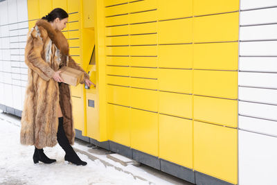 Full length of woman standing against wall