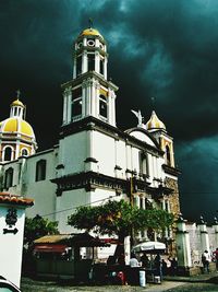 Low angle view of bell tower against cloudy sky