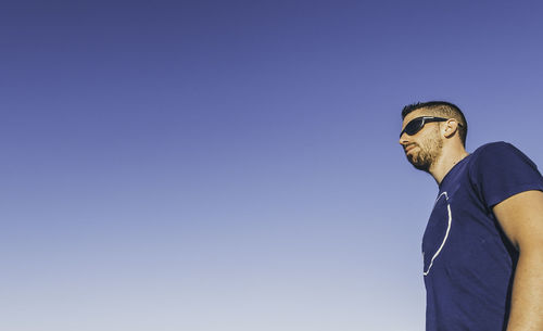 Low angle view of man standing against clear blue sky