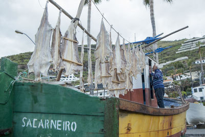 Man working on boat against sky