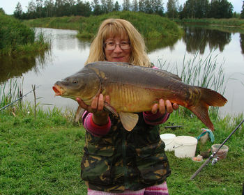 Happy woman with big carp, carp fishing, spending free time fishing, summer