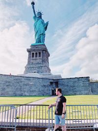 Man standing by railing against statue of liberty