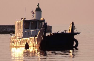 Silhouette boat in sea against clear sky during sunset