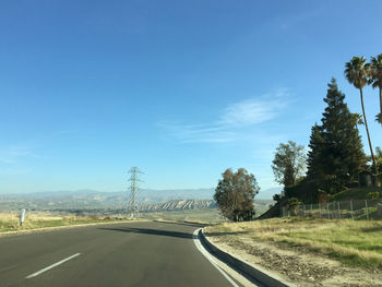 Road by trees against sky