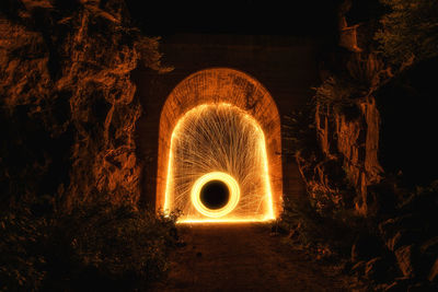 Illuminated light bulbs in tunnel at night