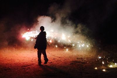 Silhouette of kid with arms raised at night