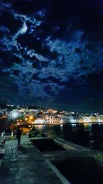 Illuminated cityscape against cloudy sky