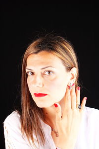 Close-up portrait of young woman against black background