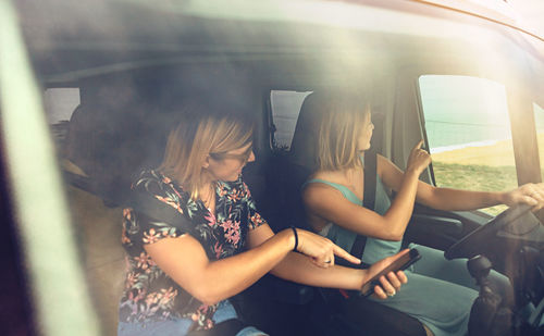 Women searching direction in smartphone while traveling in caravan