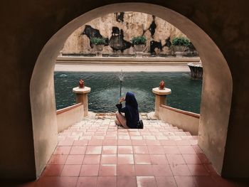 Rear view of woman sitting at entrance of building