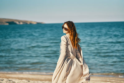 Woman standing at beach against sky