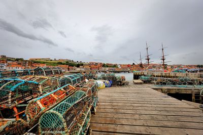 Fishing net on pier at harbor against sky