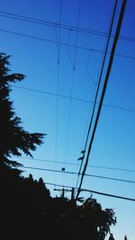 Low angle view of electricity pylon against blue sky