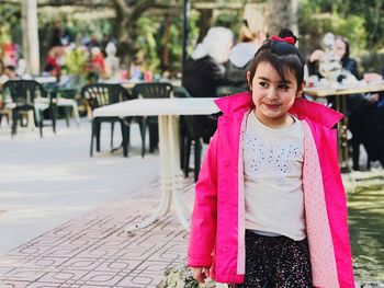 Thoughtful girl standing against outdoor cafe