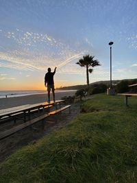 Man standing by sea against sky during sunset