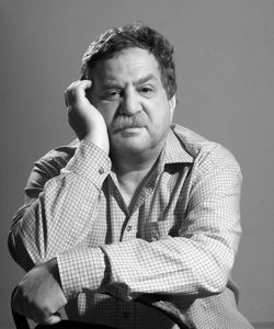 Close-up portrait of mature man sitting on chair against wall