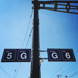 Low angle view of road sign against clear blue sky