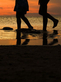 Low section of silhouette people walking on beach