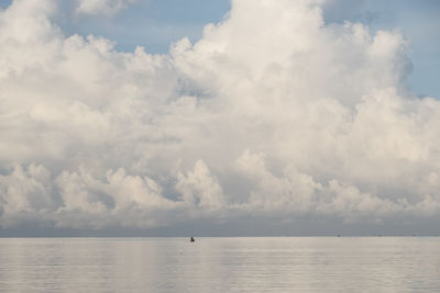 Lonesome fisher boat off shore in pacific ocean in front of dramatic clouds above the horizon