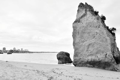 Rock formation on beach against sky