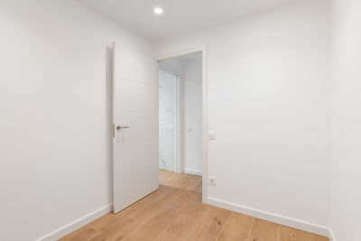 Empty room with laminate flooring and newly painted white wall in refurbished apartment 