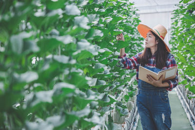 Woman wearing hat walking amidst plants