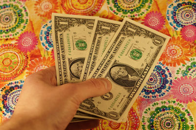 Cropped hand of man holding paper currency over floor