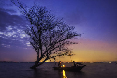 Silhouette bare tree by sea against sky during sunset