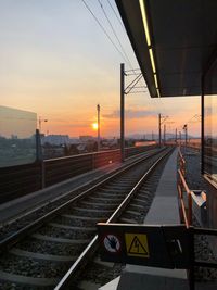 Railroad station platform against sky at sunset