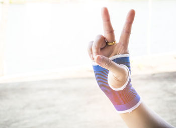 Close-up of hand showing peace sign on beach