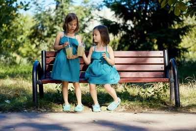 Two little girls drinking lemonade in park