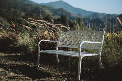 Empty chairs on field against mountains