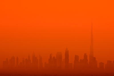 Silhouette buildings against orange sky