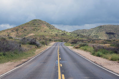 Country road by mountain against sky