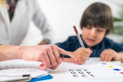 Teacher and student drawing on table in classroom