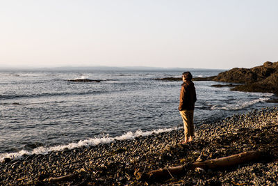 Rear view of man looking at sea against clear sky