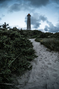 Lighthouse by sea against sky