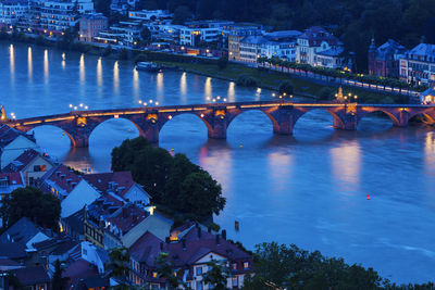 Illuminated bridge over river in city
