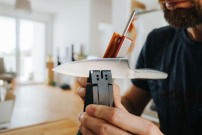 Close-up of man sharpening knife at home