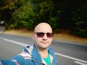 Portrait of bald man wearing sunglasses on road 