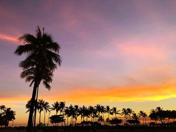 Silhouette palm trees against romantic sky at sunset