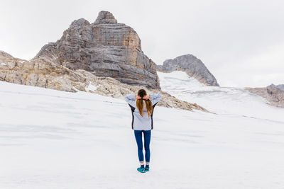 Young millennial girl enjoys the views of the alps standing on glacier