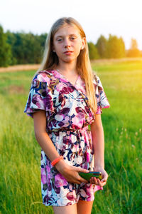 Portrait of teenage girl poses and holding smart phone. front view of charming teen girl in summer