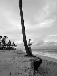 Side view full length of man standing by tree at beach