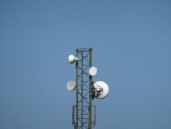 Low angle view of communications tower against clear blue sky