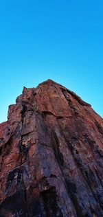 Low angle view of rock formation against clear blue sky