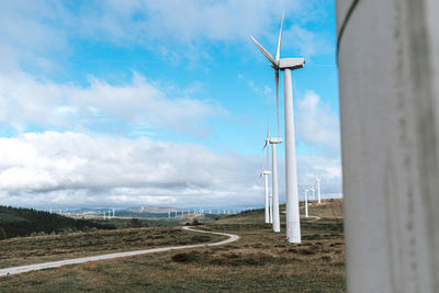 Wind turbines on field against sky